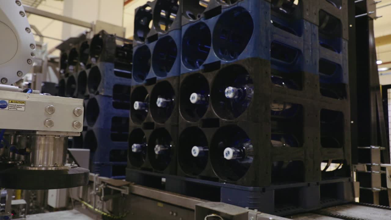 Robot grabbing several 5 gallons water bottles and placing them in a black crate automatically.