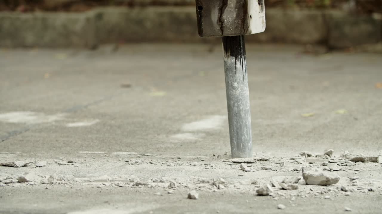 Close-up of excavator hydraulic arm rock breaker working on concrete road