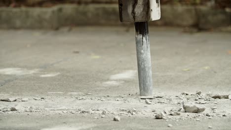 close-up of excavator hydraulic arm rock breaker working on concrete road