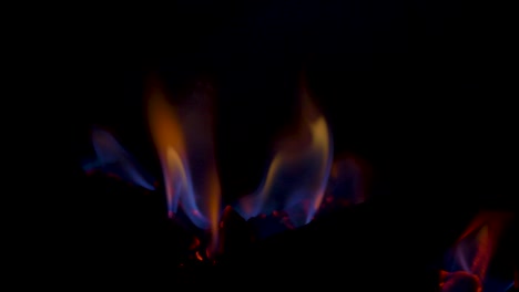 cámara lenta primer plano de la chimenea de gas llamas calientes quemando brasas en carbón falso troncos de madera detrás del panel de vidrio energía de calefacción doméstica