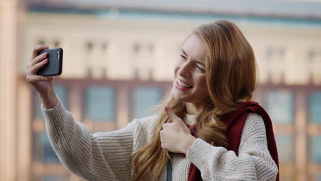 Chica-Alegre-Haciendo-Videollamadas-Por-Teléfono.-Mujer-Joven-Mostrando-El-Pulgar-Hacia-La-Cámara