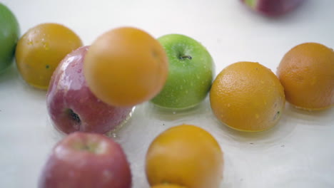 slomo of apples and oranges in water on white backdrop