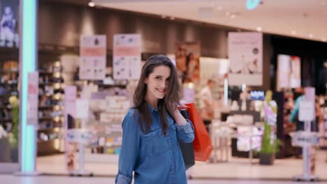 vista trasera de una mujer con bolsas de compras en un centro comercial