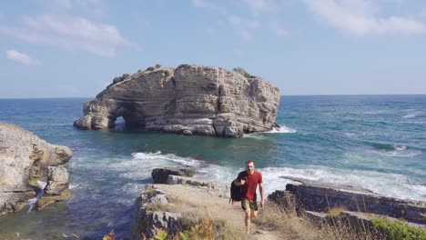 hombre viajero caminando por los acantilados junto al mar.