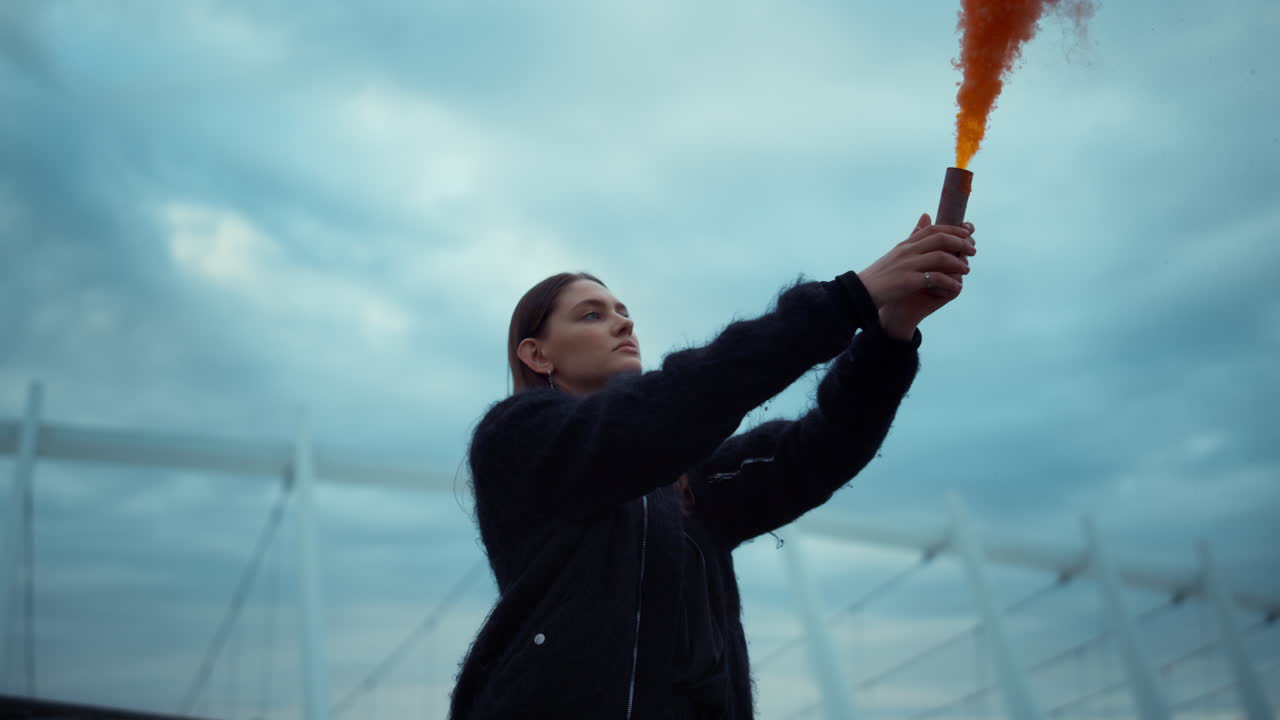 손에 연기 폭탄을 들고 있는 소녀. 연기 수류탄을 들고 손을 흔드는 집중된 여성