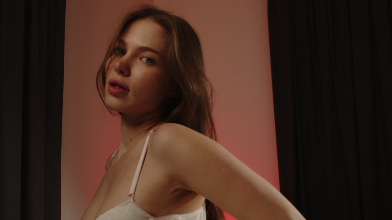 Beautiful portrait of an attractive woman wearing a white brassiere gazing at the camera in slow motion