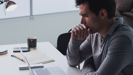 Businessman-Working-On-Laptop-At-Desk-Joined-By-Female-Colleague-Using-Mobile-Phone