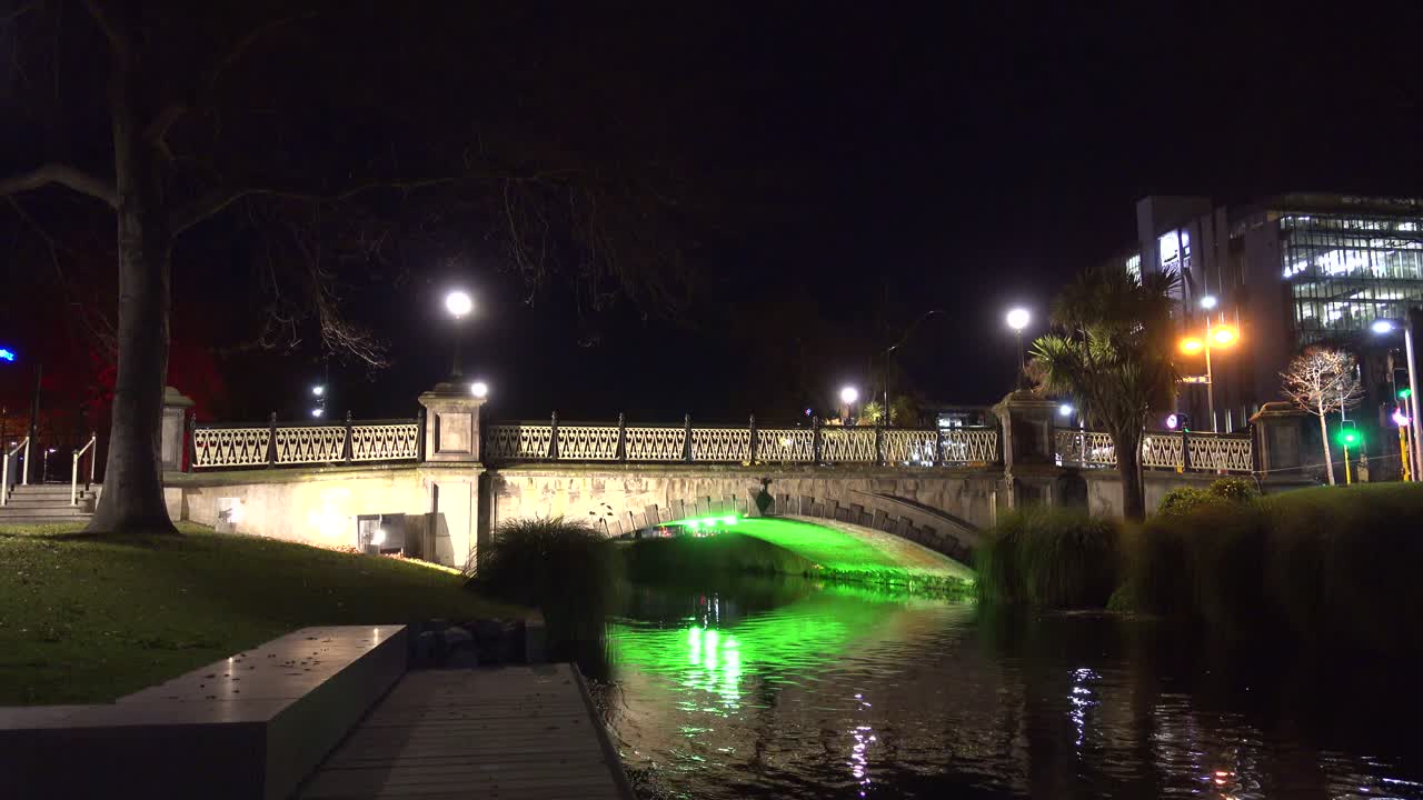 Night shot of bridge lit by green light over river