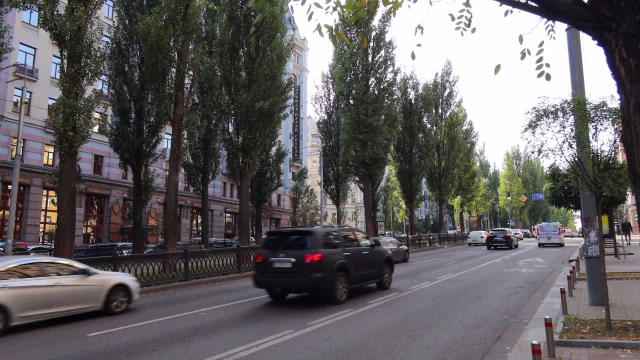 Busy street with tall trees and many cars driving in Kyiv city center Ukraine, Khreshchatyk area, 4K static shot