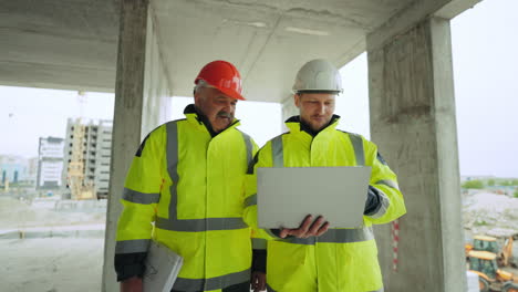 two construction engineers are inspecting under-construction building foremen are viewing construction site