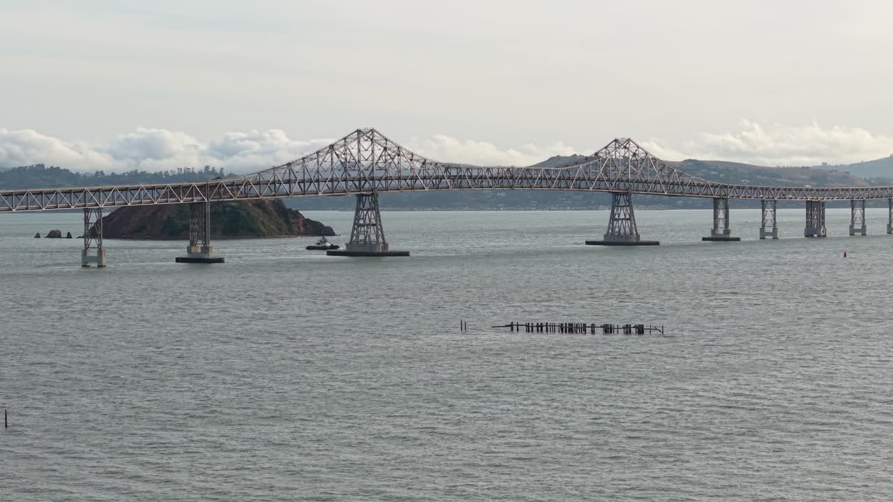 A high drone view captures the Richmond–San Rafael Bridge with moving vehicles and shimmering water below during golden hour.
