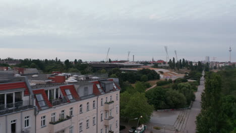 Fly-around-block-of-tenement-houses-in-urban-neighbourhood.-Public-park-and-sport-areas-around.-Berlin,-Germany