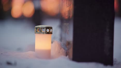 vela led frente a una tumba nevada al atardecer