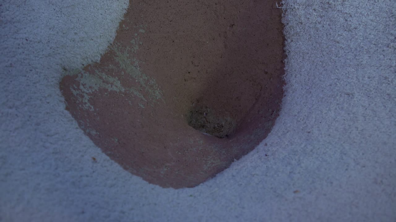 An orange ball rolling into an obstacle at a mini golf course and eventually rolls down a pipe to another hole.