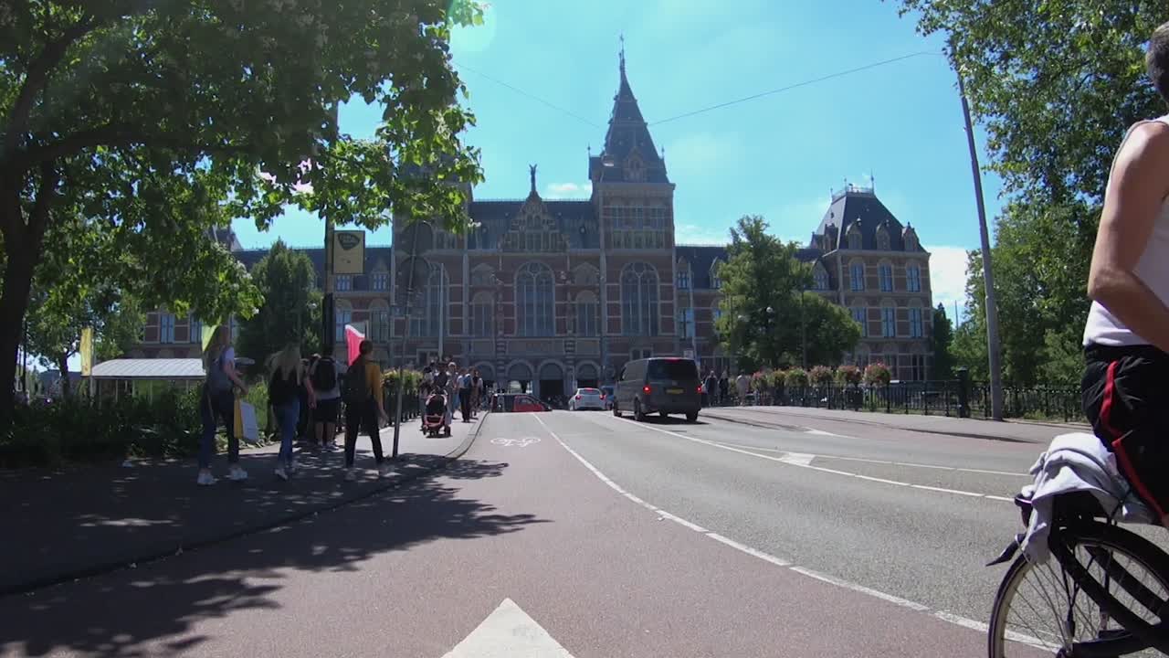 Cyclists Circulating on a Bike Only Road, Pedestrians Walking and Cars Driving on the Street in Front of the Rijksmuseum on a Summer Day