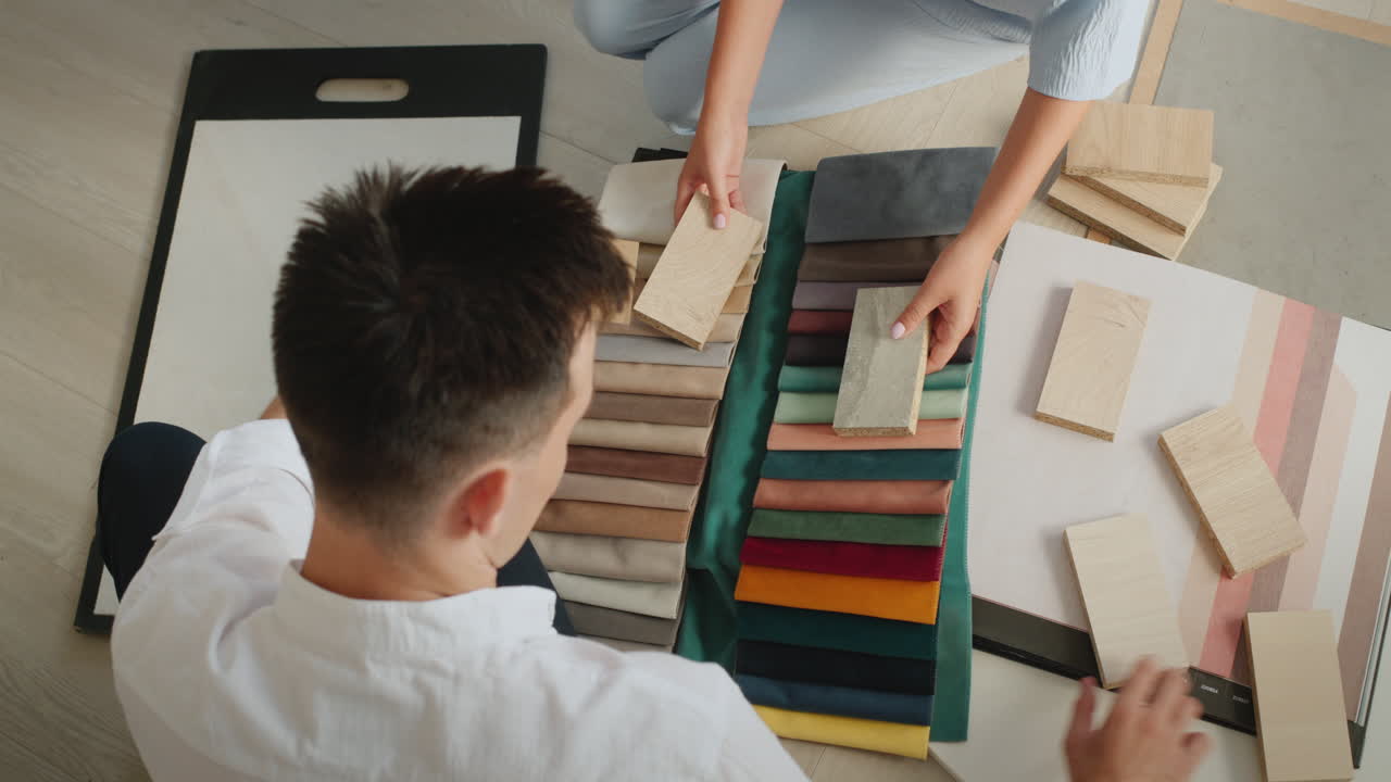 The design team selects finishing materials for their project, compares samples of fabric, wood and wallpaper
