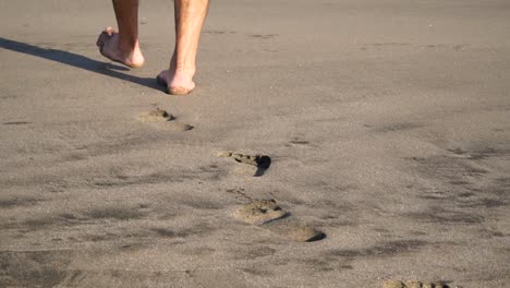 close up of feet from behind walking on beach