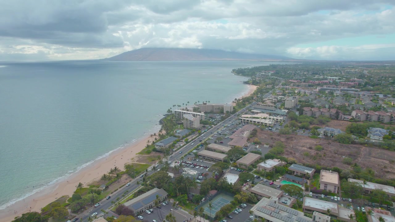 Riprese drone che si inclinano verso l'alto, mostrando un campo da tennis, una spiaggia e poi un vulcano alle Hawaii