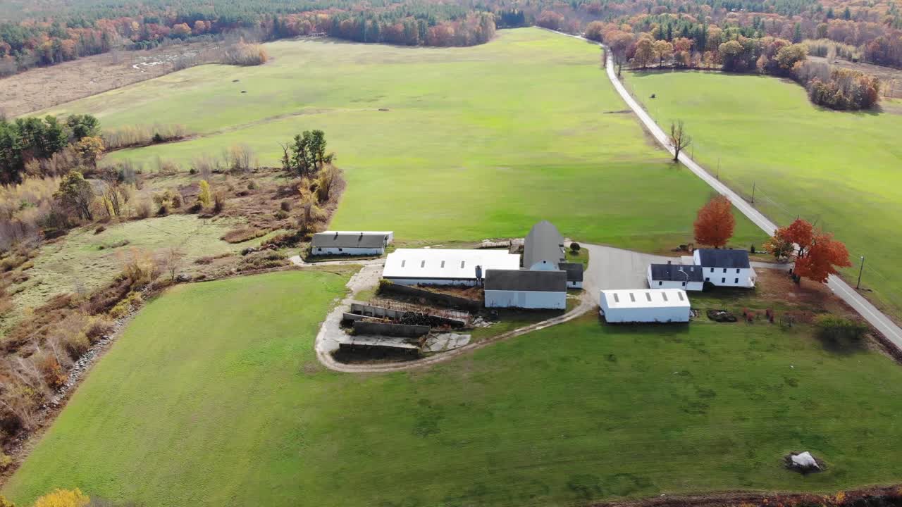 Breve ripresa con drone che rivela montagne e l'orizzonte sopra un ampio complesso agricolo e un grande campo