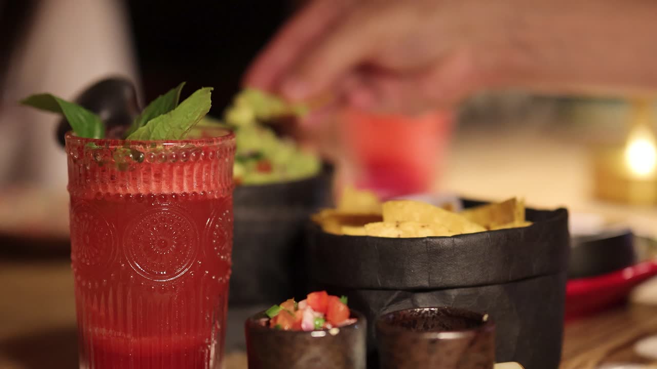 A vibrant scene of guacamole, chips, and cocktails in a warmly lit restaurant setting