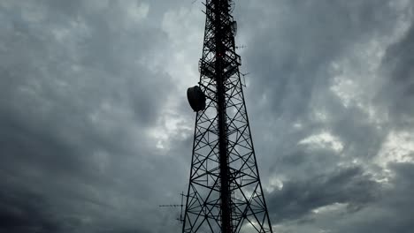 ominous timelapse of a silhouetted telecommunications tower with clouds in the background