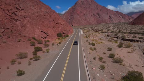 Disparo-De-Un-Dron-Siguiendo-Un-Automóvil-Gris-Que-Conducía-Por-La-Quebrada-Las-Angosturas-En-Catamarca,-Argentina,-En-Una-Carretera-Con-Curvas.