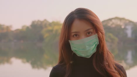 woman wearing a face mask in a park by a lake