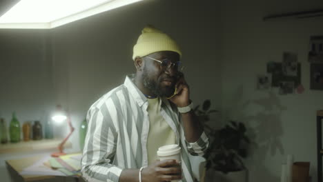 man on a phone call holding coffee in a modern office