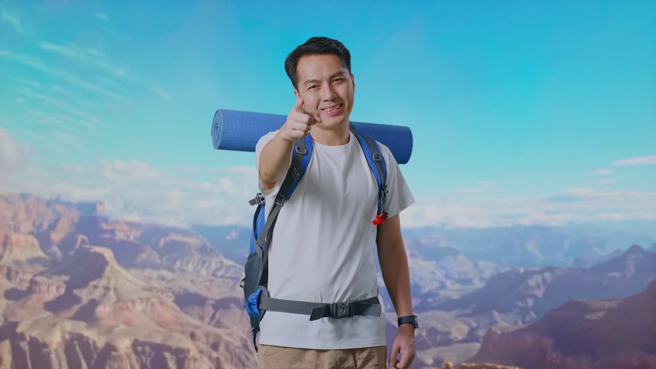 Asian Male Hiker With Mountaineering Backpack Smiling, Touching His Chest, And Pointing To Camera While Traveling At The Top Of Mountain