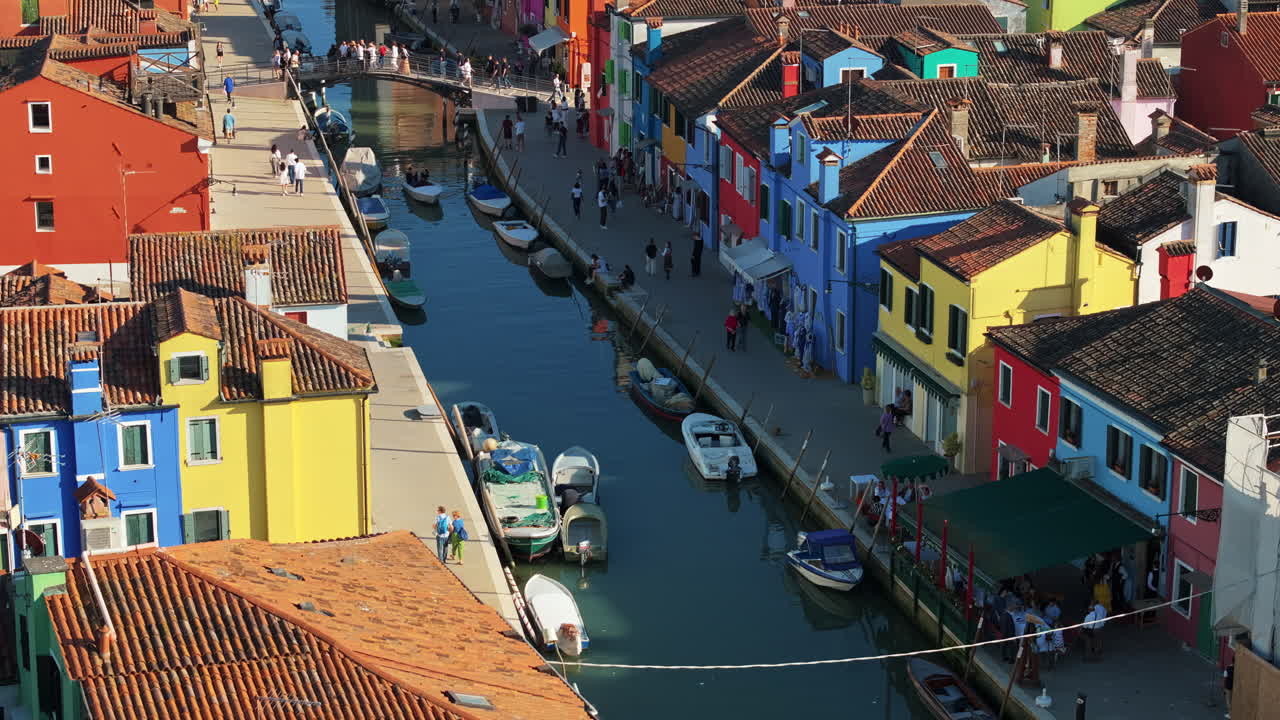 Aerial drone view of boats on the sides of a canal near the colourful houses of Burano island, Italy