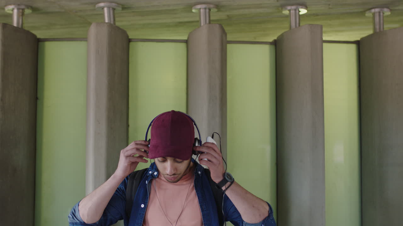 atractivo joven hombre hispano retrato de estudiante escuchando música en auriculares