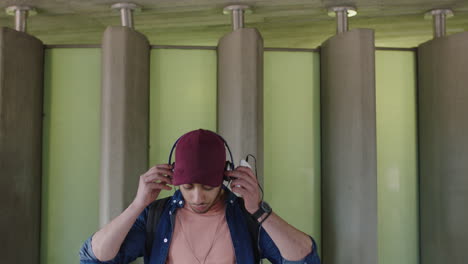 attractive young hispanic man portrait of student listening to music on headphones