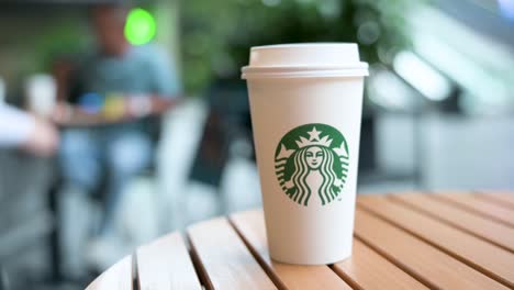 a starbucks coffee paper cup is placed on a table at the american coffee chain's store in shenzhen, china.