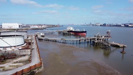 Crude-oil-tanker-ship-loading-at-petrochemical-refinery-harbour-terminal-aerial-view-pull-back