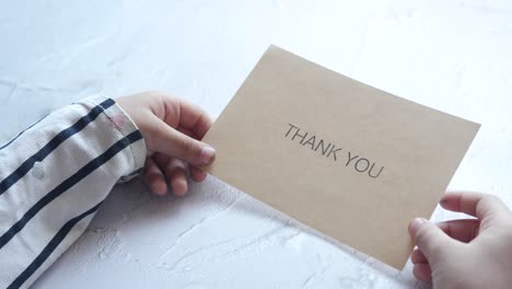 child hand holding thank you letter on table ,