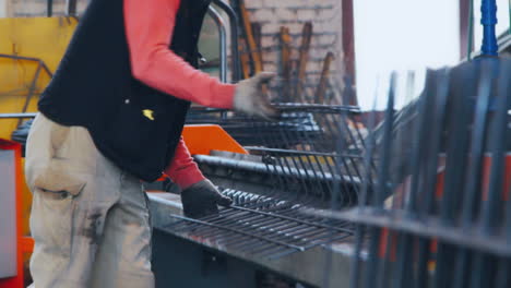 factory worker bending grid from steel bars. workman bends metal at factory