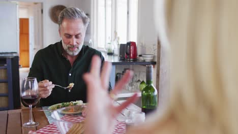 feliz pareja caucásica madura sonriendo, hablando y disfrutando de la comida juntos