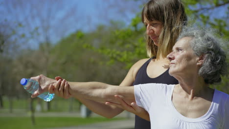 Professional-trainer-working-with-senior-woman-in-summer-park.