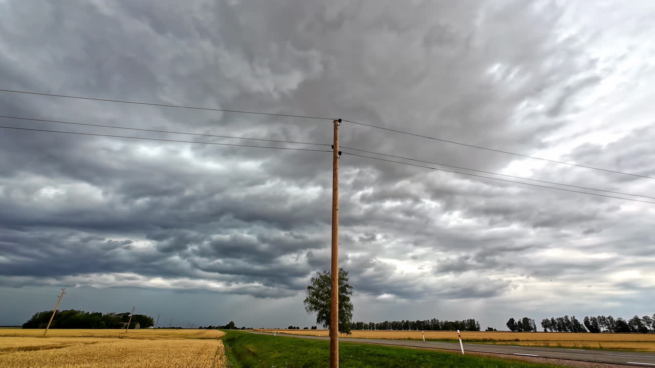 Old electricity line near road with grey clouds above, time lapse