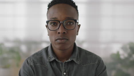 Porträt-Eines-Jungen-Afroamerikanischen-Praktikanten-Im-Bereich-Business-Studenten,-Der-Vor-Dem-Hintergrund-Eines-Büroarbeitsplatzes-Den-Kopf-Dreht-Und-Ernst-Und-Nachdenklich-In-Die-Kamera-Blickt