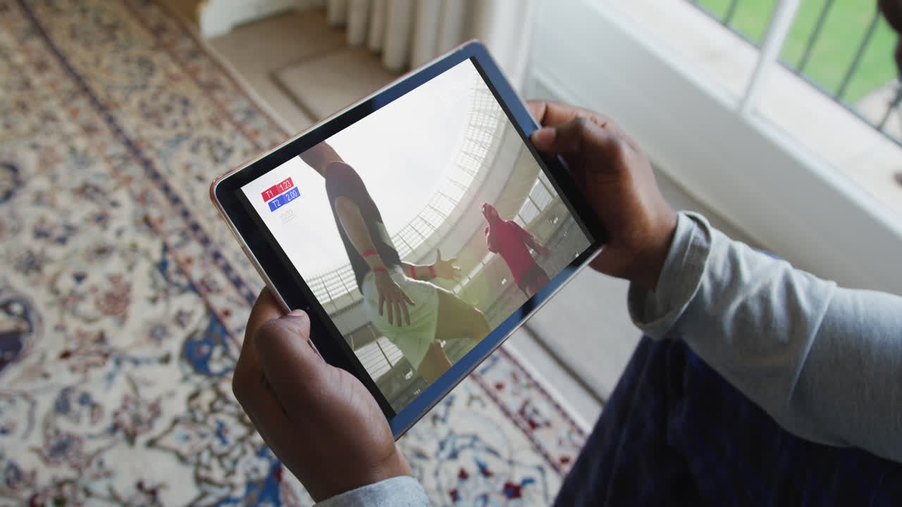 compuesto de un hombre sentado en casa, viendo un partido de rugby en la tableta