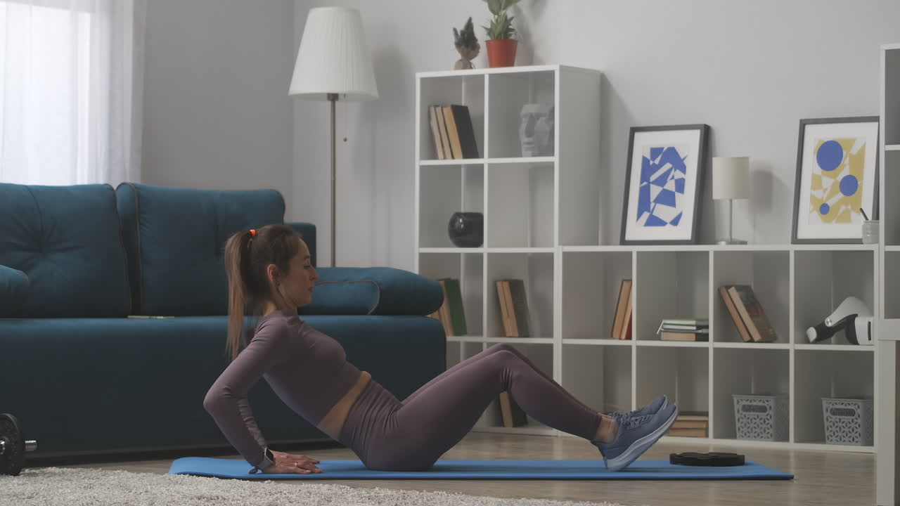 casa gimnasio joven mujer deportiva está haciendo abdominales para los músculos abdominales mujer atlética está sentada en el suelo y levantando el torso y las piernas estilo de vida saludable
