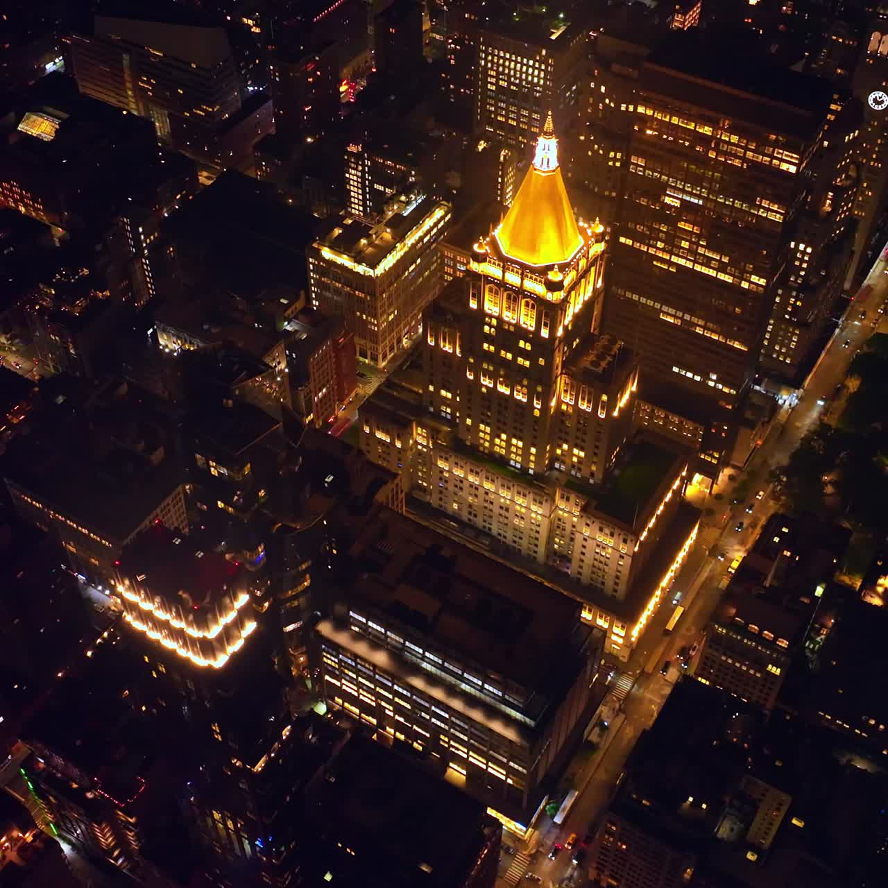 New York Life Building with shining golden roof at night. Beautifully-lit structure standing out at the backdrop of other architecture. Top view