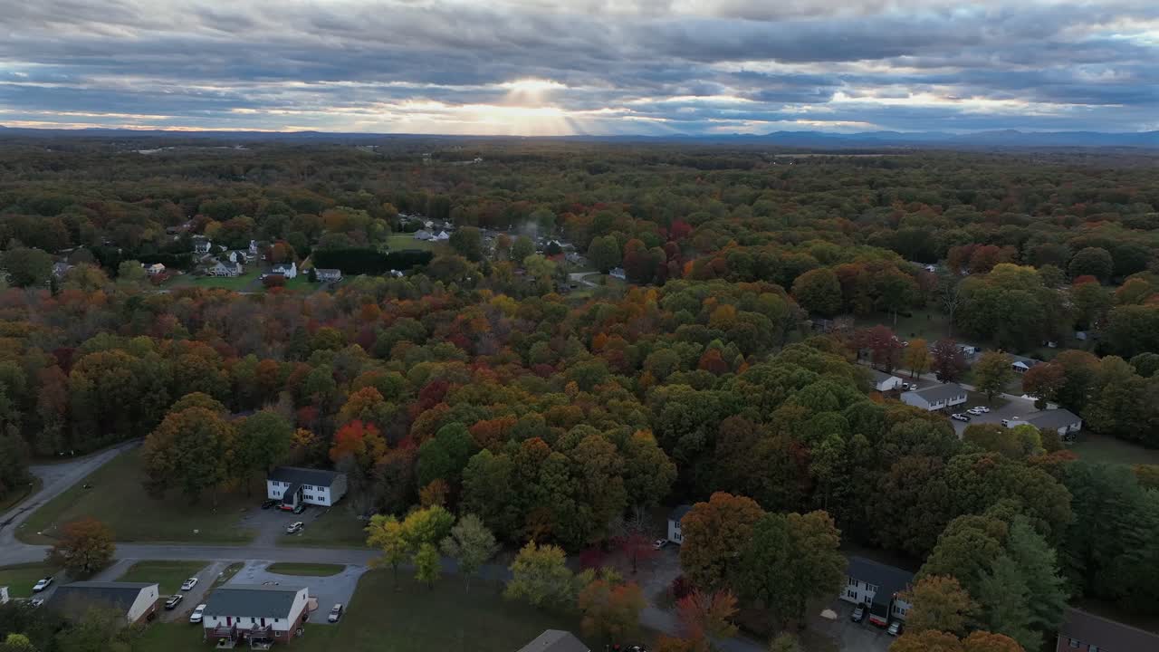 Quiet suburb neighborhood in autumn season. American forest landscape with colored trees. Houses and homes in American architecture at cloudy day at dusk. Aerial wide shot