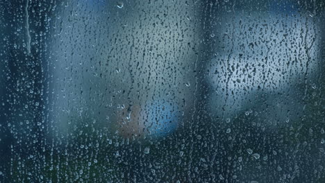 closeup raindrops trickling down on wet clear window glass on a rainy day