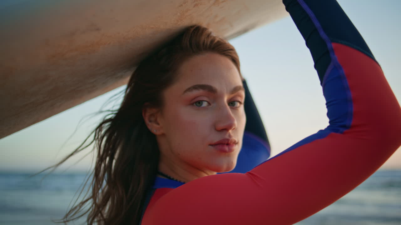 Surf girl looking ocean waves at morning portrait. Windy hair woman relaxing