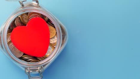 corazón rojo en un frasco de monedas: un símbolo de caridad y donación