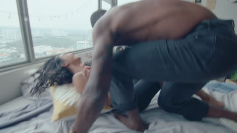 young couple playing pillow fight and tickling on bed