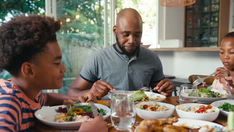 close up of family sitting around table at home enjoying meal together