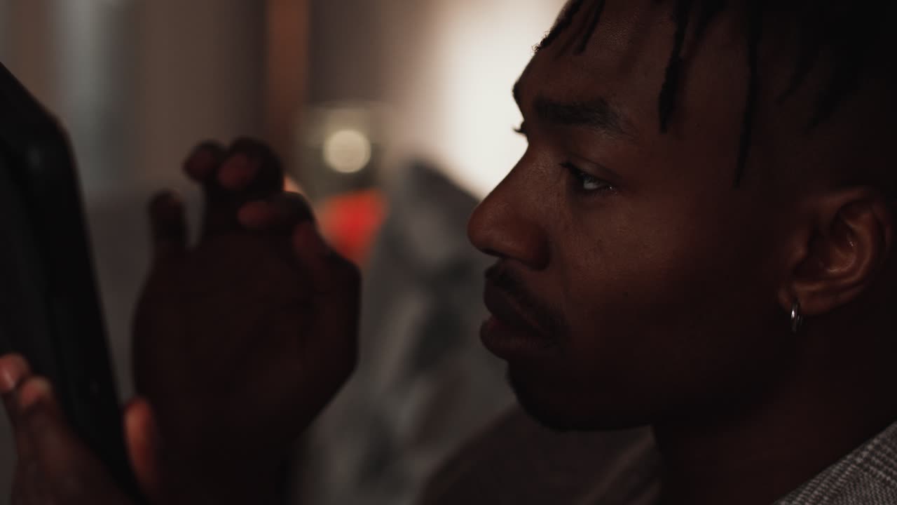 un joven hombre negro desliza y toca un dispositivo de tableta en casa